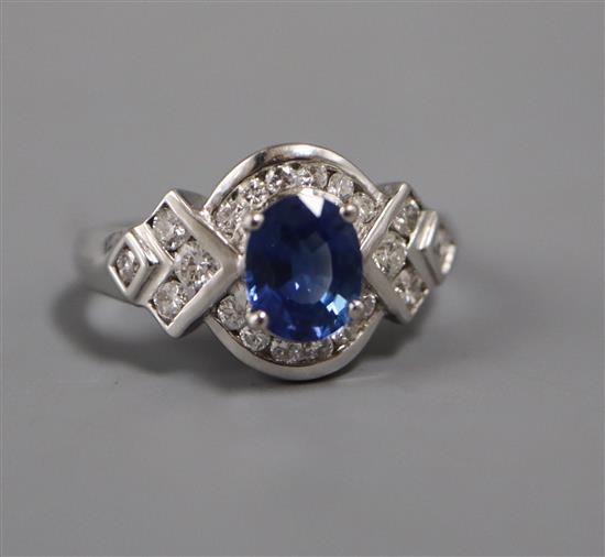 A modern 18ct white gold, sapphire and diamond oval cluster ring, with diamond set shaped shoulders, size L.